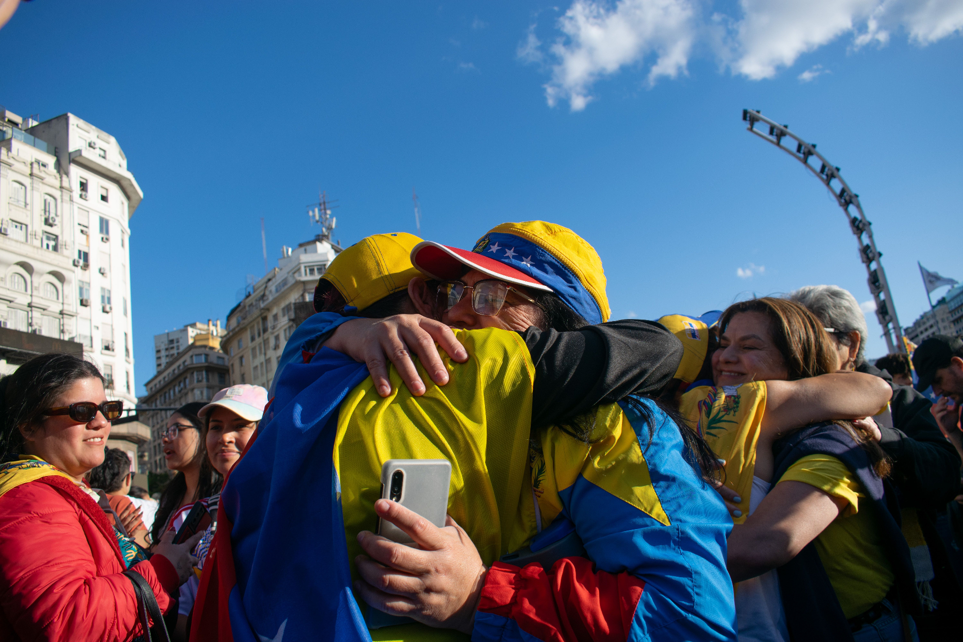 Personas venezolanas abrazándose con banderas del país